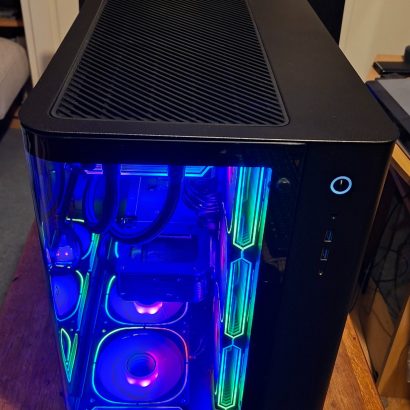 Mid-tower PC with a glass side panel showing blue RGB lighting and an angled top vent.